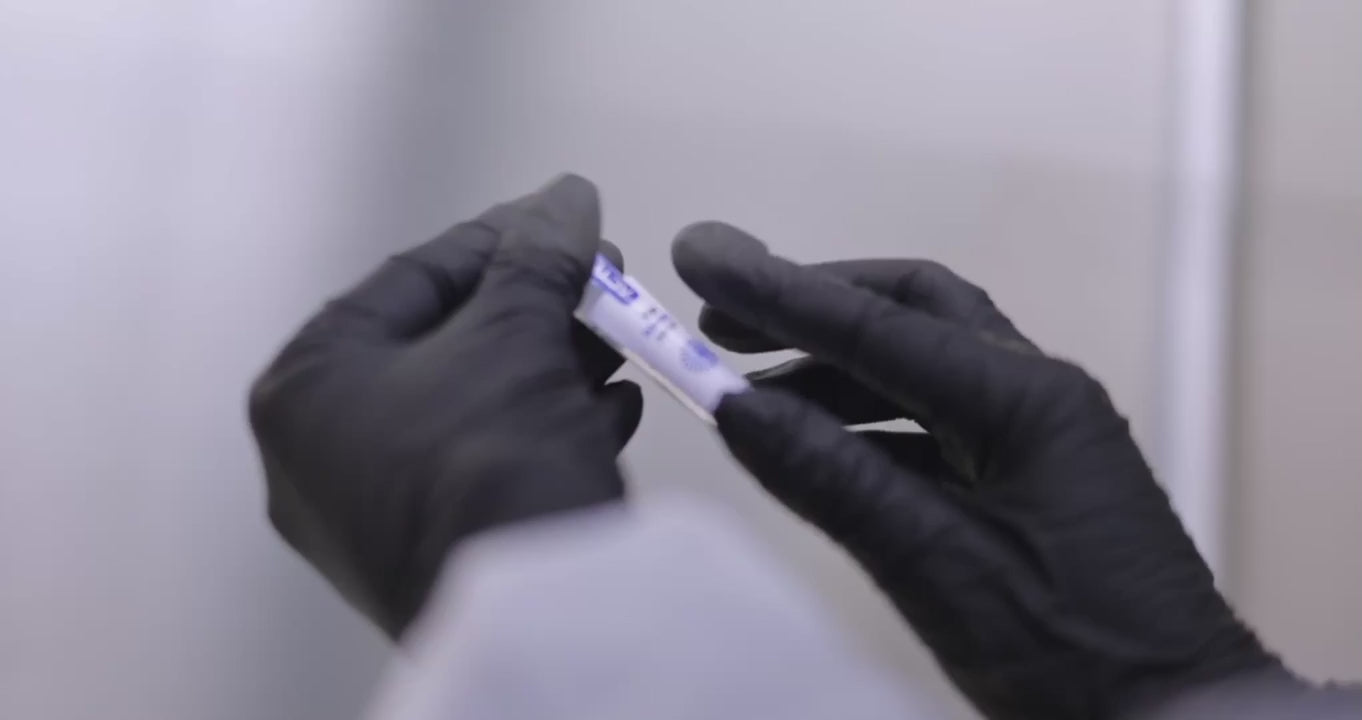 Gloved hands holding a labelled cryovial